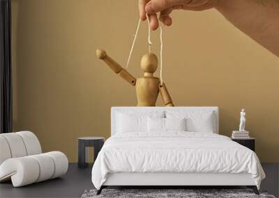 wooden puppet figure is hanging from the hand of an adult manipulating Wall mural