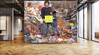 Father 40 years old and son child 7 ecologist holding a sign with the words save the planet go green, protest against climate change, global warming and atmospheric pollution in a garbage dump waste Wall mural