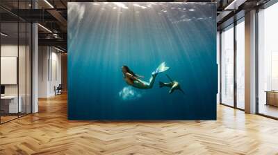 Mermaid swimming underwater in the deep blue sea with a seal Wall mural