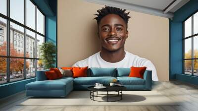 Poster for advertising, Young adult african male dreadlocks smiling with his arms folded on a beige background; cheerful black person looking at camera Wall mural