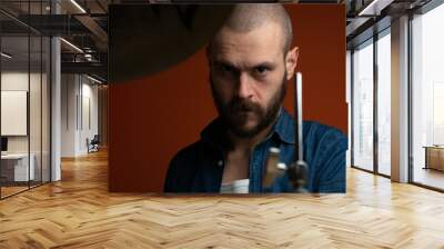 Boy playing drum with jeans shirt and dark background Wall mural