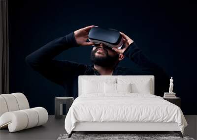 Young hipster bearded man wearing virtual reality goggles. Black background studio VR concept. Wall mural