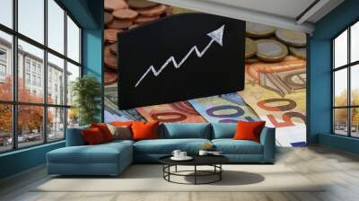 growing arrow on blackboard with euro banknotes and coins Wall mural