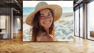 A woman wearing a straw hat is smiling on a beach Wall mural