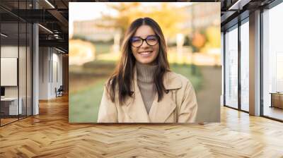 Cheerful LGBT female student wearing glasses joyfully smiling beautifully in front of campus Wall mural