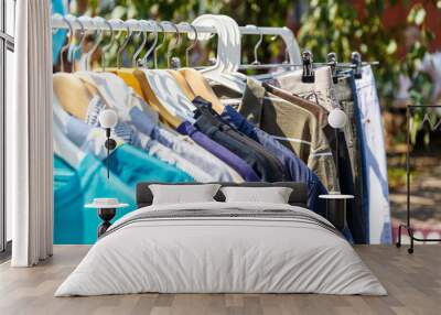 Hangers with men's and women's clothing at the garage sale Wall mural