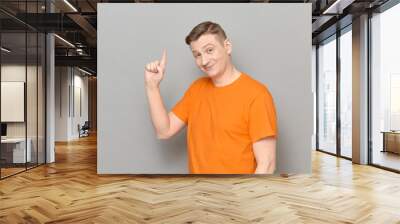 Portrait of happy cheerful man raising index finger up and smiling Wall mural