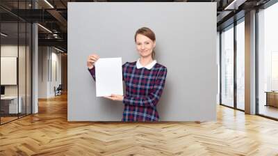 Studio portrait of happy young woman holding white blank paper sheet Wall mural