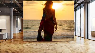 Beautiful young woman on the beach of the ocean at sunset Wall mural