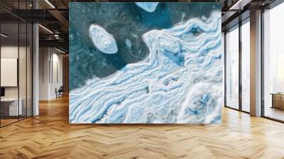 Top view of the icy seashore. Winter aerial photograph of the sea coast. Ice floes in freezing sea water. Nature of the Extreme North and the Arctic. Cold frosty winter weather. Natural background. Wall mural