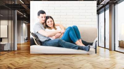 young couple relaxing on sofa at home enjoy their time together and embracing each other. stay at home Wall mural