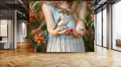 Young girl gently holding small bird, symbolizing care for animals and wildlife protection Wall mural