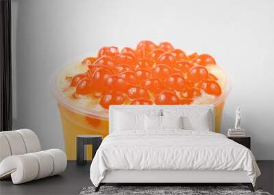 Closeup of a cup of delicious orange bubble tea with boba on top of it on a white background Wall mural