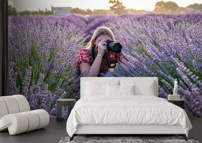 A young beautiful female professional photographer taking pictures in a lavender field on a scenic summer sunrise. Wall mural