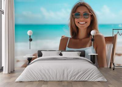 Happy woman relaxing on beach chair near ocean wearing sunglasses Wall mural