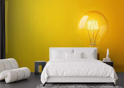 Light bulb shining brightly on a yellow background Wall mural