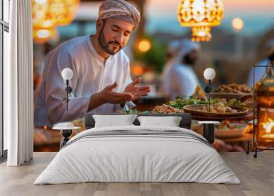 Muslim man praying before iftar dinner with friends during ramadan feast Wall mural