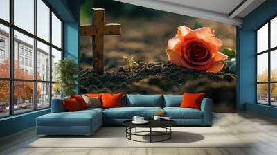 Single rose lying on the ground near a cross at sunset Wall mural