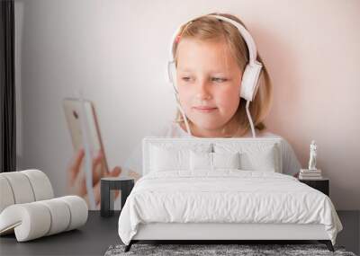 Cheerful portrait of happy caucasian blondie teen girl witn earphones listening to music with expression. Childhood leisure, happiness concept Wall mural