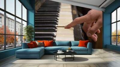 Close-up shot of a finger pressing an old vintage piano key Wall mural