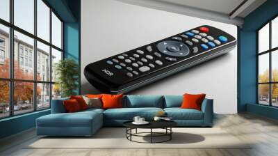 Close-up of a black remote control for a DVD player, showing detailed buttons and ergonomic design, on a white background. Wall mural