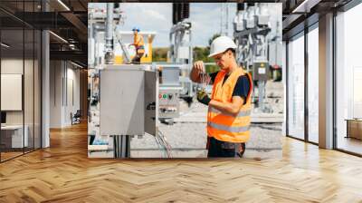 Adult electrical engineer inspect the electrical systems at the equipment control cabinet. Installation of modern electrical station Wall mural