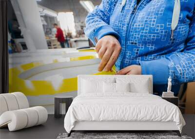 Applying colored yellow membrane to a surface of plastic 3d letter of signboard. worker's hands close up Wall mural