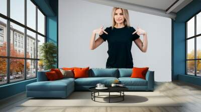 Stylish blonde girl wearing black t-shirt posing in studio Wall mural