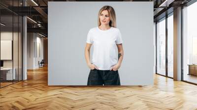 Stylish blonde girl wearing white t-shirt posing in studio Wall mural