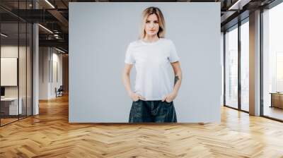 Stylish blonde girl wearing white t-shirt posing in studio Wall mural