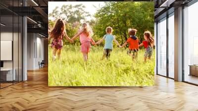 a group of children playing and running in the park on a green gozon. Wall mural