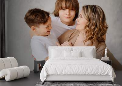 A mother and sons in beige and white clothes pose for a photo shoot Wall mural