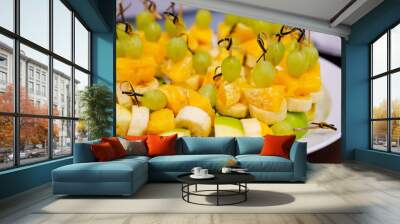 A plate with fruity canapes made from apples, bananas, oranges and grapes. Wall mural