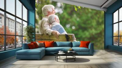 Elderly couple resting on a bench in the park Wall mural