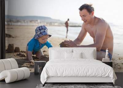 Father and son playing with sand at the beach Wall mural