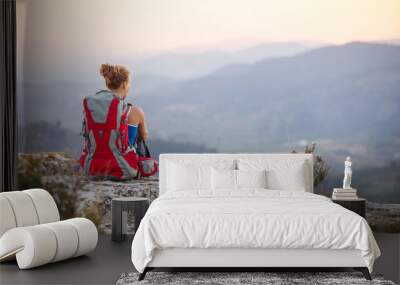 Woman tourist sitting on top of a mountain Wall mural