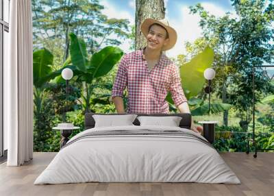 farm lifestyle concepts. happy young farmer smiles as he looks out over his banana crops. enterprising adult Wall mural