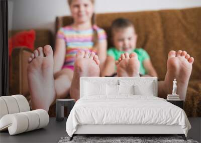 Close-up focus on the toes of two children sitting next to the sofa - faces out of focus Wall mural