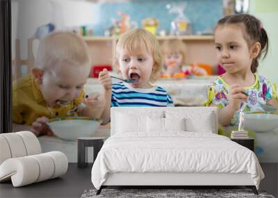 group of children eating from plates in day care centre Wall mural