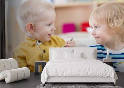 Two funny smiling very positive kids eating in kindergarten Wall mural