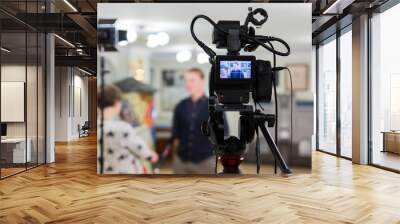 Video of the interview. Television equipment, camcorder with LCD screen, lighting equipment. Wall mural