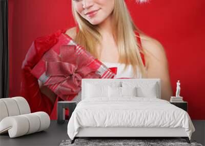 Young beautiful girl dressed as Santa holds a gift. Wall mural