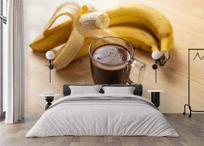 The cup of coffee and ripe yellow bananas on a wooden table Wall mural