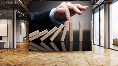 Businessperson Stopping Wooden Blocks From Falling On Desk Wall mural