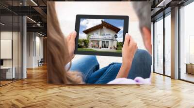 couple looking at house photo on digital tablet Wall mural