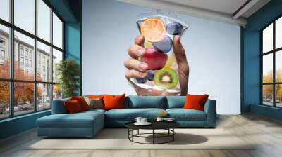 Human Hand Holding Saline Bag With Fruit Slices Over Grey Background Wall mural