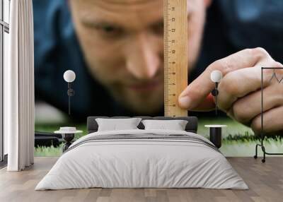 Man Using Measuring Scale While Cutting Grass Wall mural