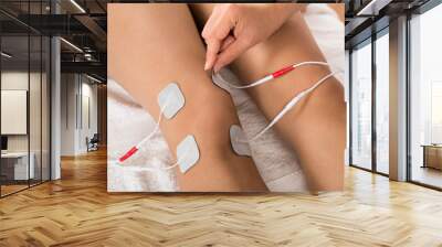 therapist placing electrodes on woman's knee Wall mural