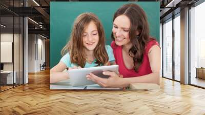 woman assisting girl in using digital tablet Wall mural