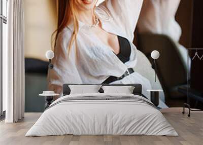 Portrait of sexy redhead young woman in white shirt on a chair.  Wall mural